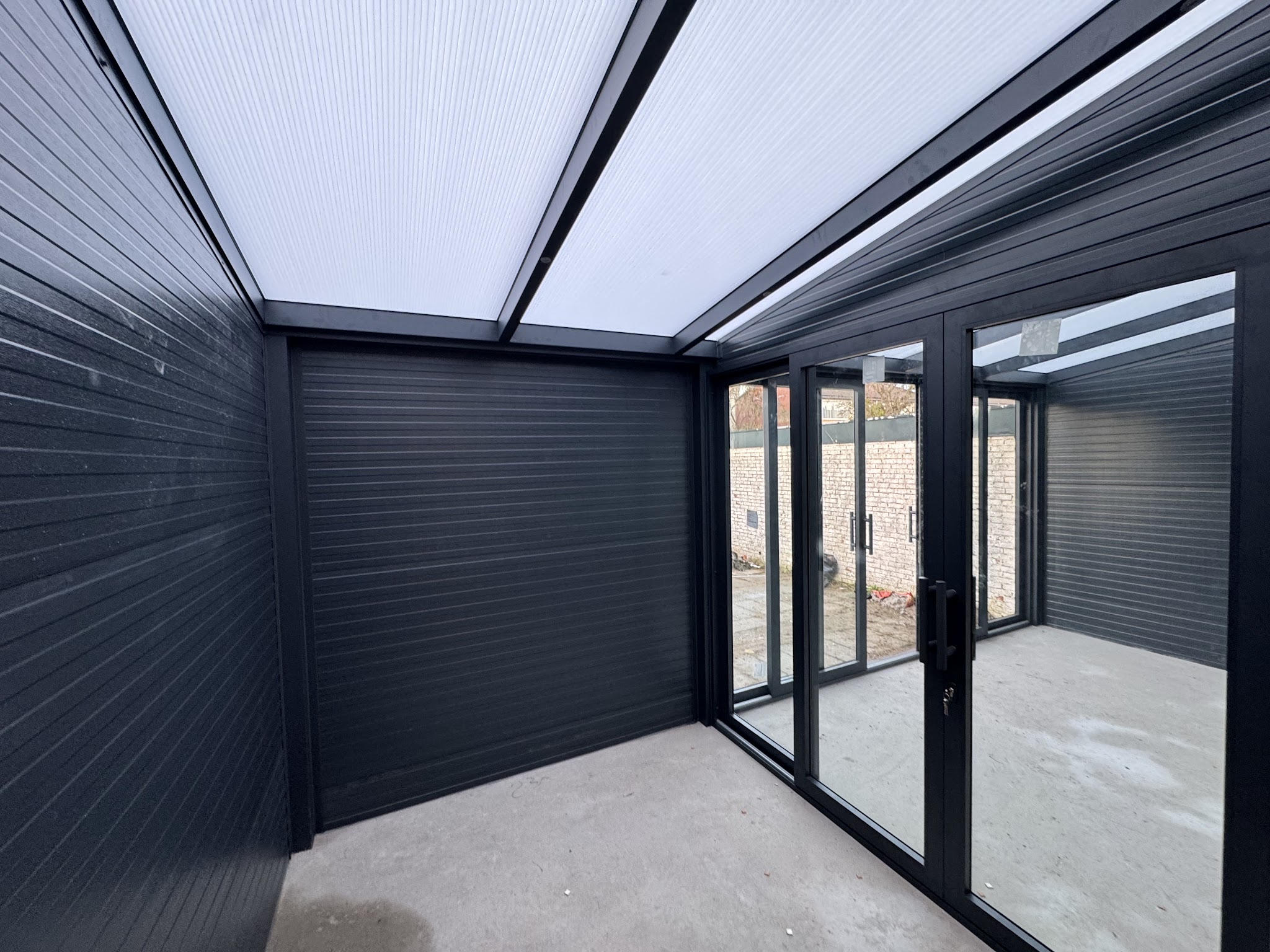 Binnenkant van een veranda met dichte aluminium zijwanden en een lichtdoorlatend dak