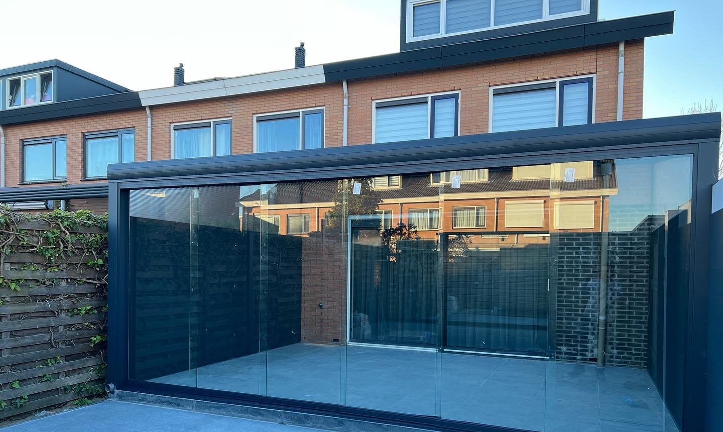 Brede veranda met glazen schuifwanden over het hele terras van een rijtjeshuis