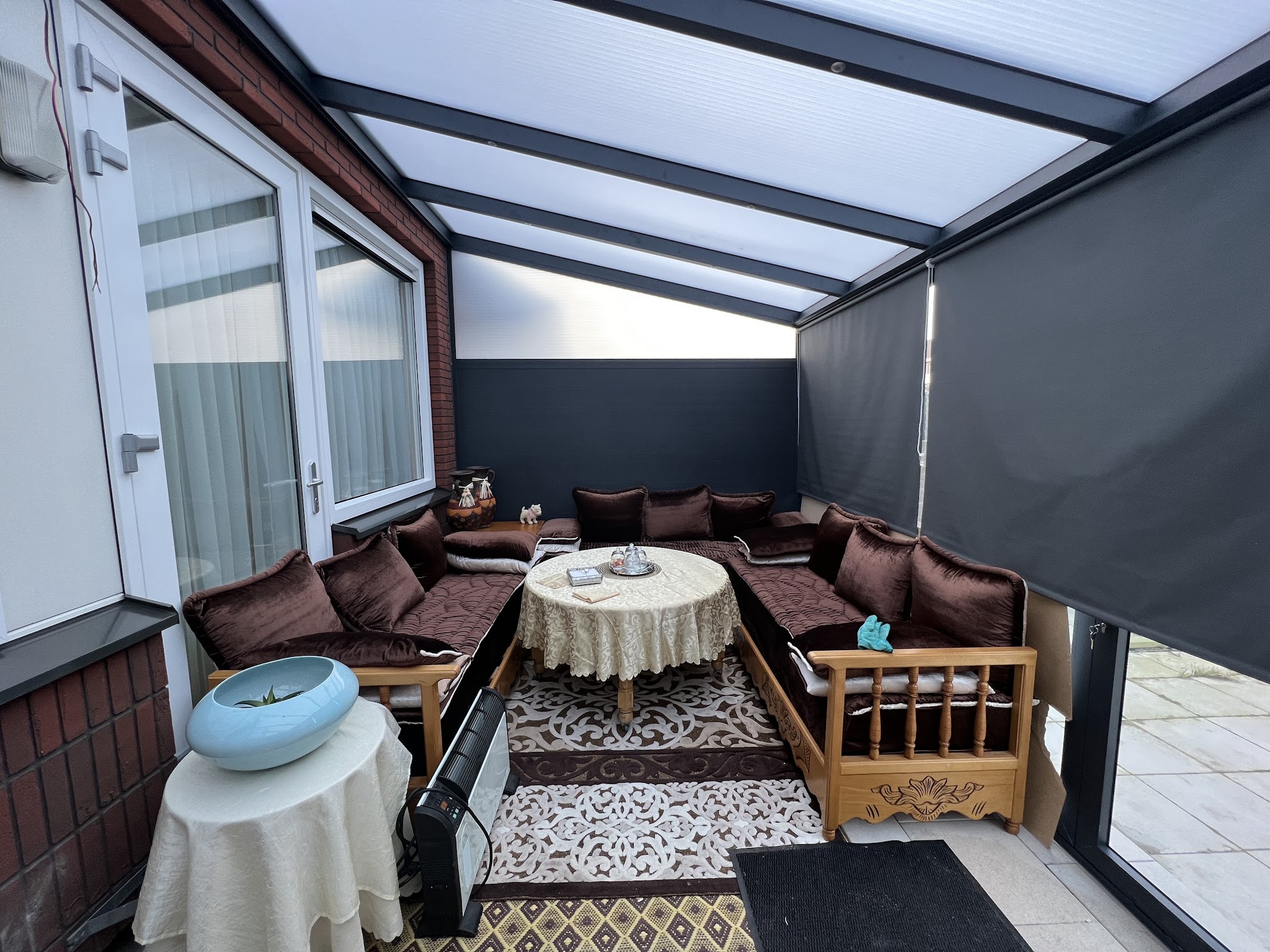 Veranda in gebruik als zithoek met loungebank, lichtdoorlatend dak en een screen aan de zijkant